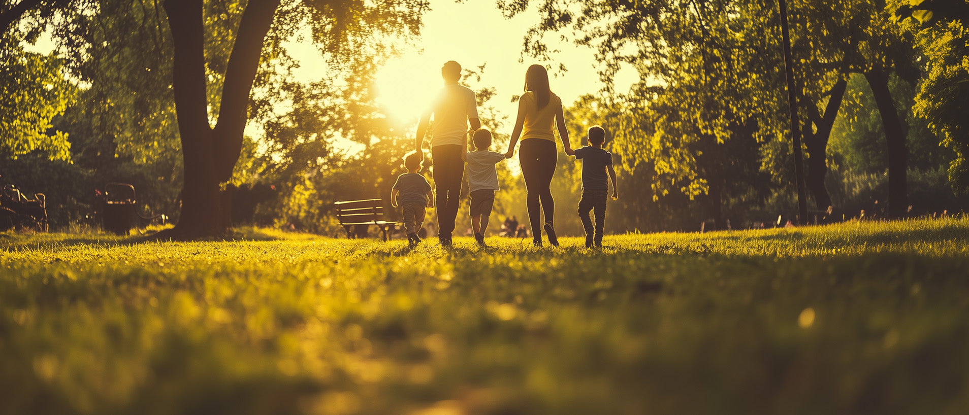 Two parents and their three children walk in a park on a sunny evening